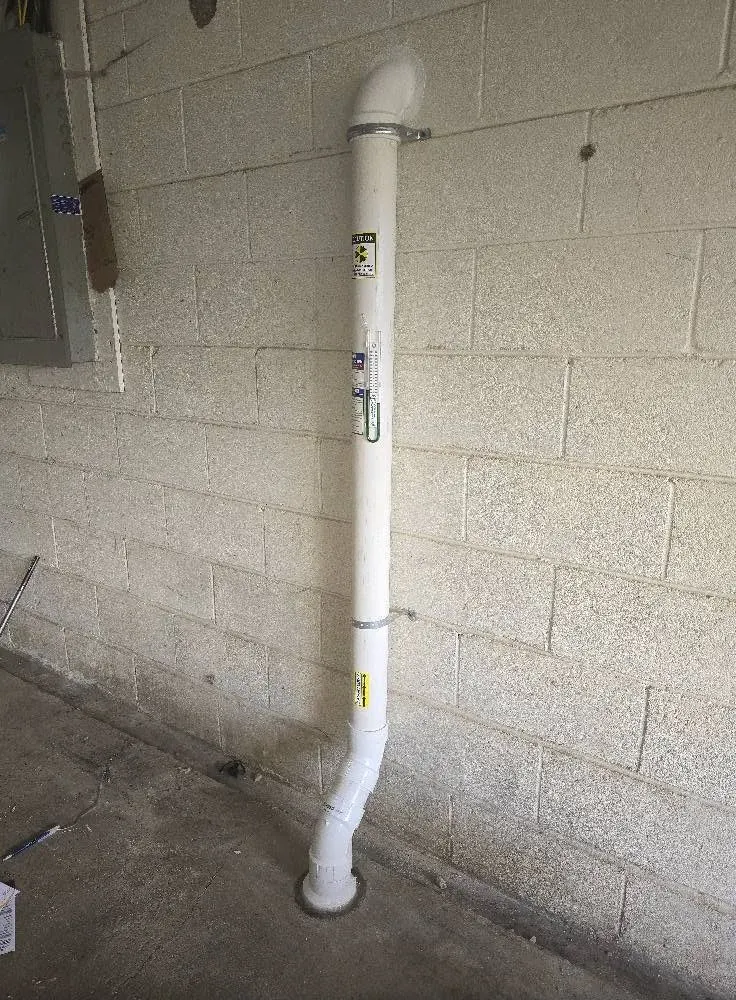 Interior radon mitigation suction pipe with a U-tube manometer