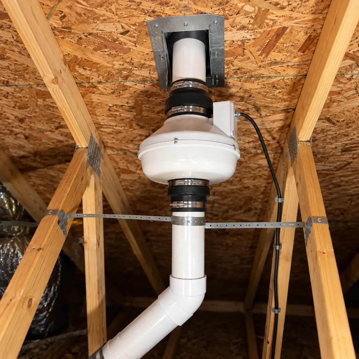 Radon mitigation fan and vent pipe installed in an attic